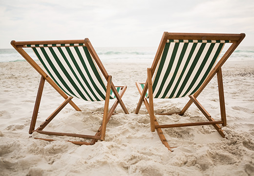 opvouwbare houten strandstoelen met een crèmekleurig canvas zitvlak